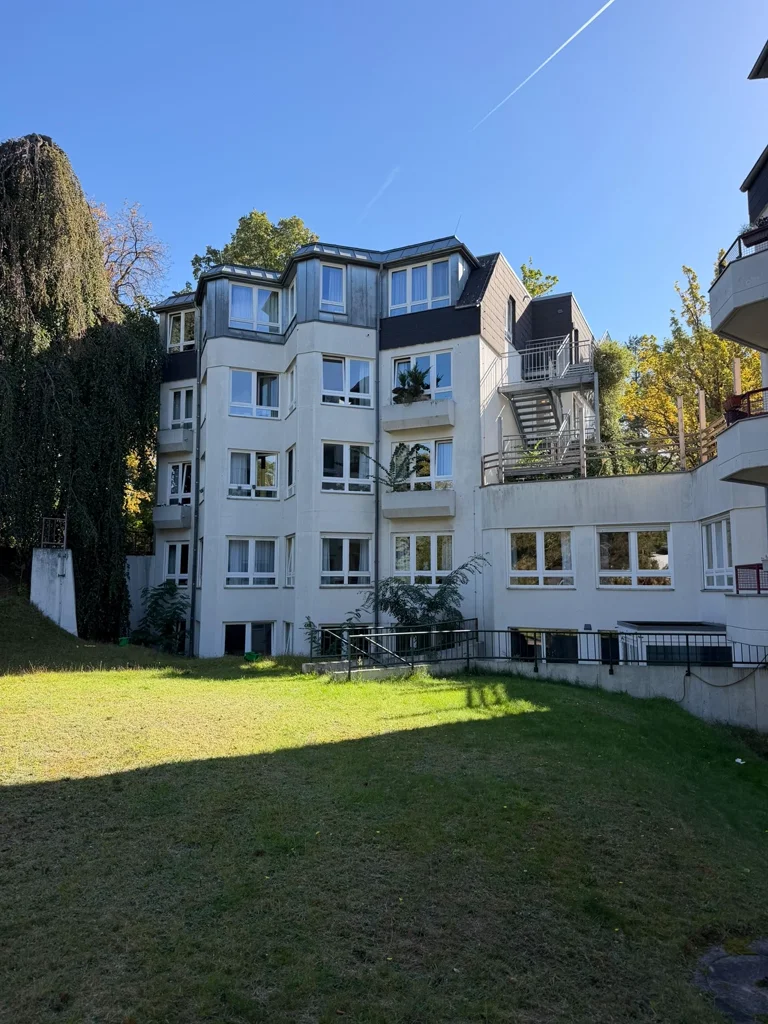 Außenansicht eines Gebäudes mit mehreren Fensterreihen und Grünfläche.
