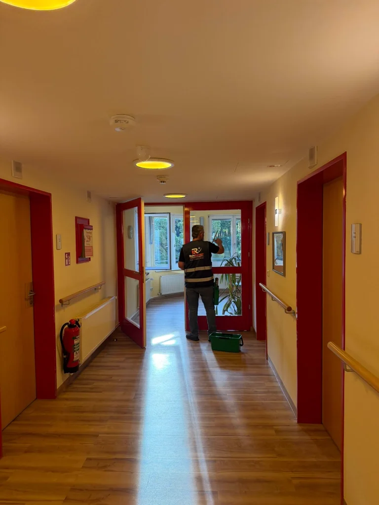 Ein Mitarbeiter bei der Glasreinigung am Ende eines Flurs.